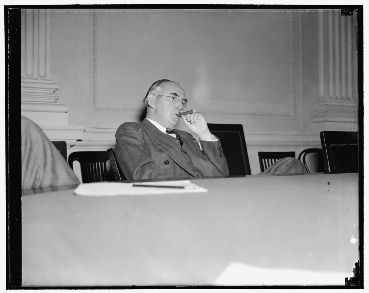 Senator Arthur Vandenberg seated with a cigar at a committee table