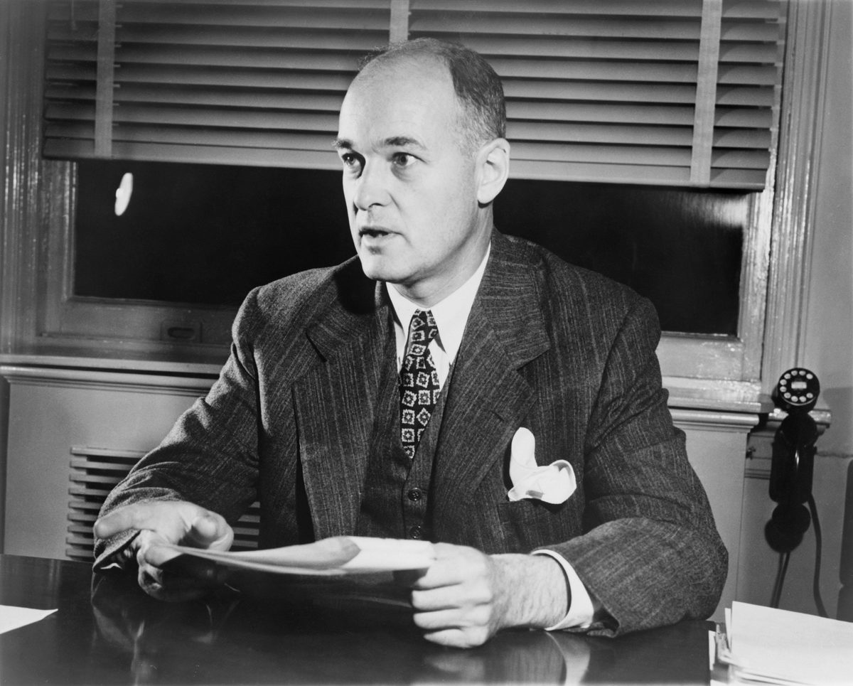 George Kennan seated at his desk reviewing papers