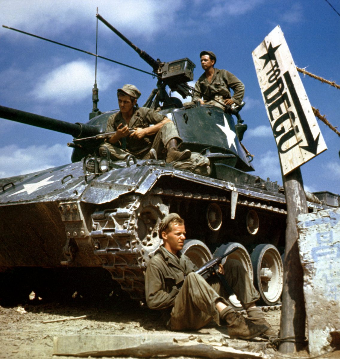 American soldiers with a tank during the Korean War, beside a sign pointing to Taegu