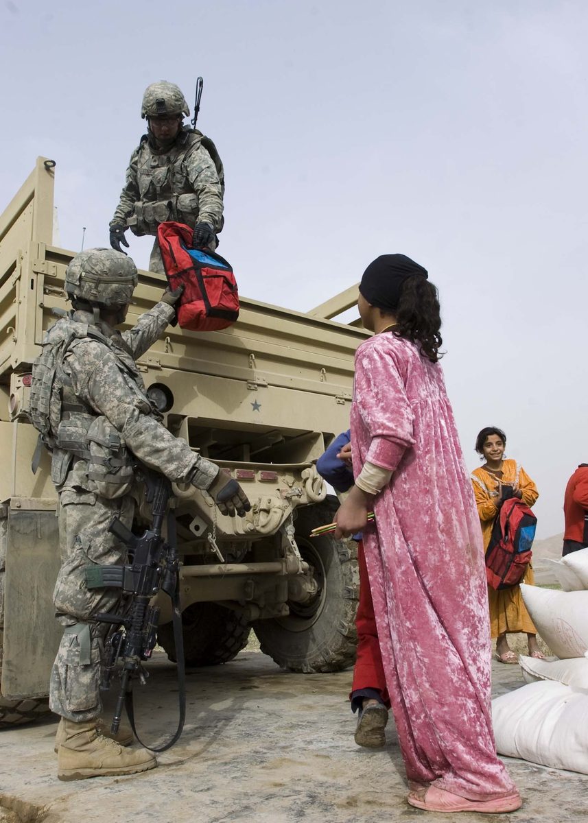 U.S. soldiers hand out backpacks and school supplies to local children during the Global War on Terror